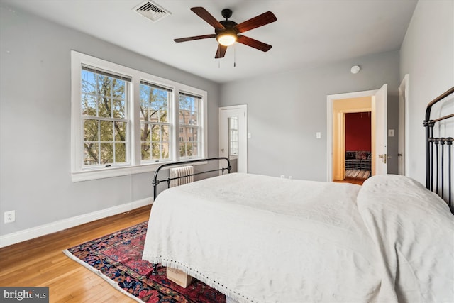 bedroom with wood finished floors, ceiling fan, baseboards, and visible vents