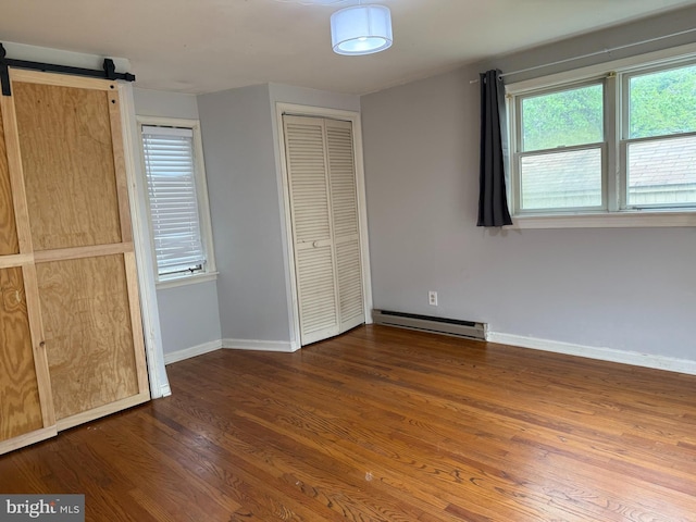 619 Cannon St, Chestertown, MD 21620 - unfurnished bedroom featuring a barn door, wood finished floors, baseboards, and a baseboard heating unit