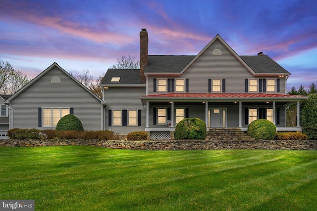 view of front of home featuring a front yard, a porch, and a standing seam roof