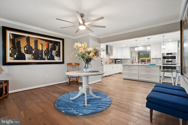 dining space with crown molding, baseboards, light wood-type flooring, and a ceiling fan