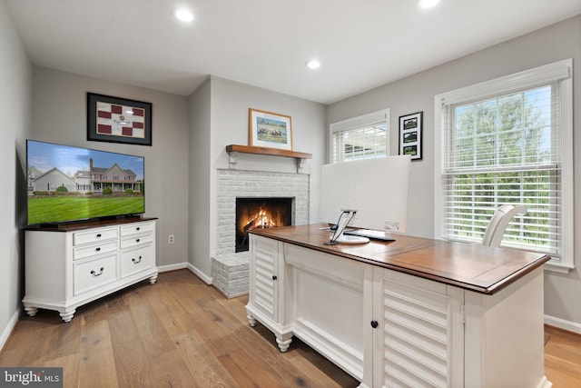 office area featuring recessed lighting, light wood finished floors, a brick fireplace, and baseboards