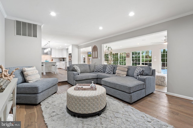 living area with ornamental molding, visible vents, recessed lighting, and wood finished floors
