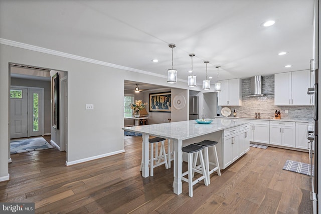 kitchen featuring a kitchen island, dark wood-style floors, wall chimney exhaust hood, and a healthy amount of sunlight