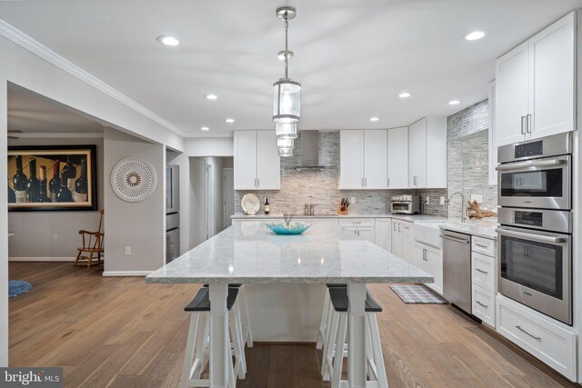 kitchen featuring wood finished floors, a sink, crown molding, and appliances with stainless steel finishes