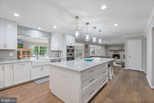 kitchen featuring a sink, crown molding, light wood finished floors, stainless steel appliances, and a kitchen island
