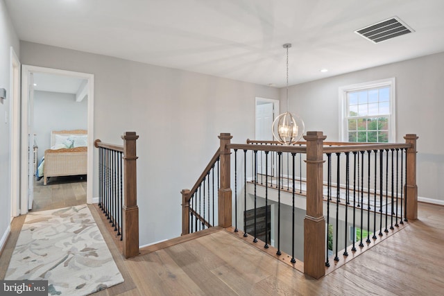 staircase with visible vents, recessed lighting, a chandelier, wood finished floors, and baseboards