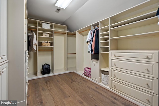walk in closet with wood finished floors and vaulted ceiling