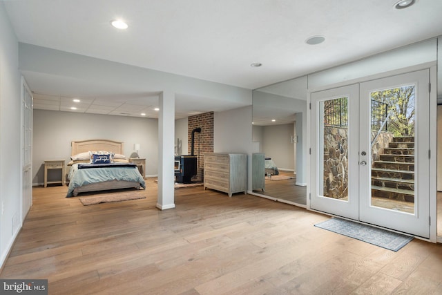 bedroom with recessed lighting, a wood stove, access to outside, and wood finished floors