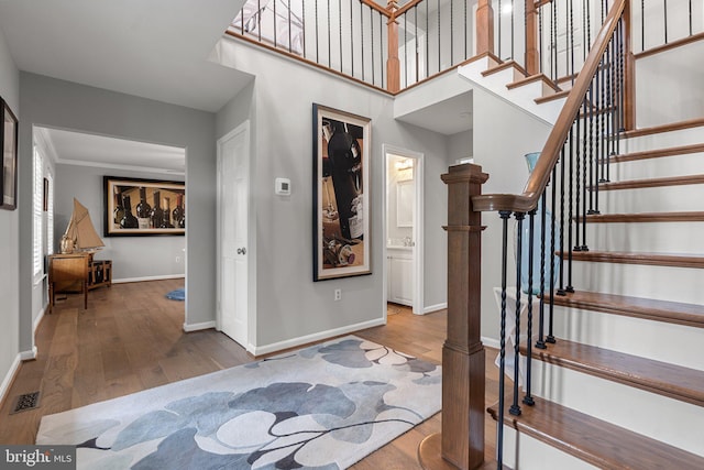 foyer featuring a towering ceiling, visible vents, wood finished floors, stairs, and baseboards