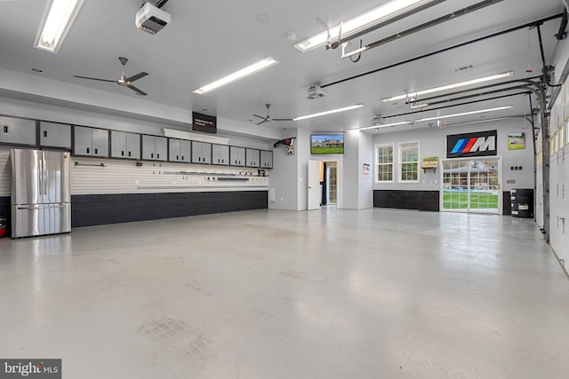 garage with a garage door opener, freestanding refrigerator, and a ceiling fan