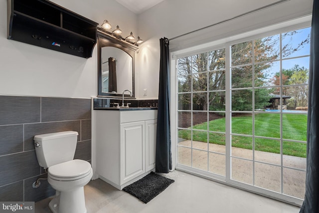 bathroom with vanity, tile walls, toilet, and wainscoting
