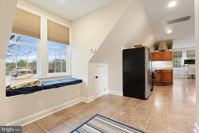 kitchen featuring visible vents, baseboards, light countertops, freestanding refrigerator, and brown cabinets