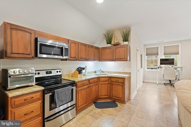 kitchen featuring a sink, brown cabinetry, light stone countertops, a toaster, and stainless steel appliances