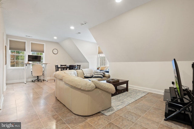 living area featuring baseboards, lofted ceiling, and a healthy amount of sunlight