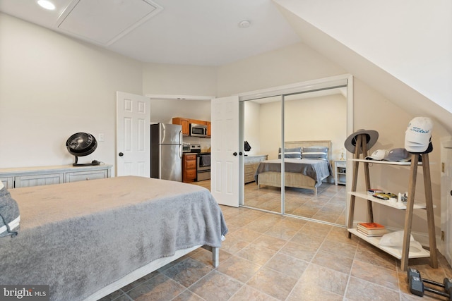 bedroom featuring a closet, freestanding refrigerator, and lofted ceiling