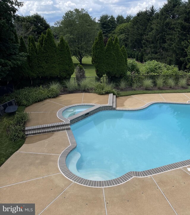 outdoor pool with a patio area and fence