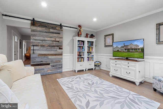 living room with a barn door, crown molding, a wainscoted wall, and wood finished floors