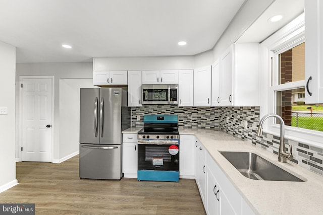 kitchen with white cabinets, decorative backsplash, a sink, and appliances with stainless steel finishes