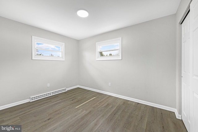 unfurnished bedroom featuring a baseboard radiator, a closet, wood finished floors, and baseboards