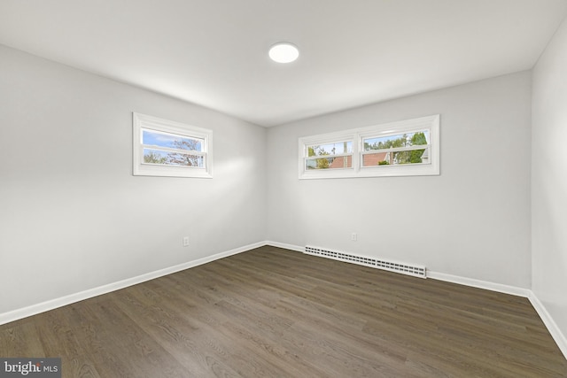 unfurnished room featuring a baseboard heating unit, baseboards, and dark wood-style flooring