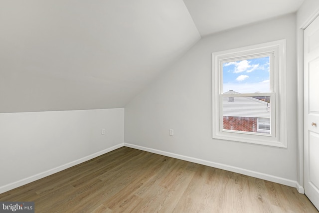bonus room with light wood-type flooring, baseboards, and vaulted ceiling