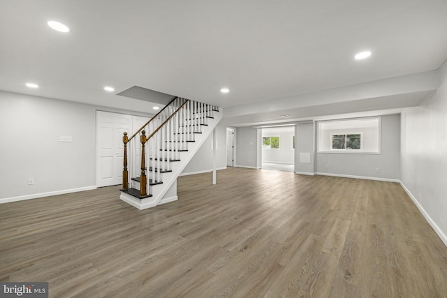 basement with wood finished floors, recessed lighting, baseboards, and stairway