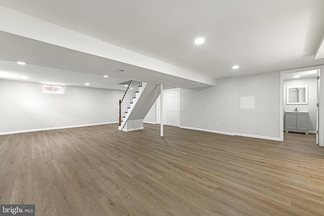 finished basement with recessed lighting, stairs, baseboards, and wood finished floors