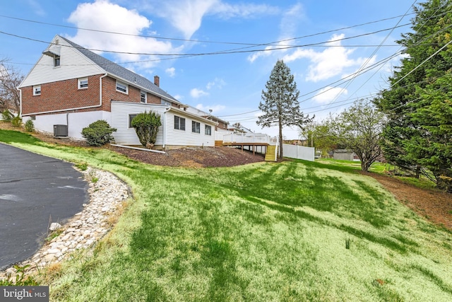 exterior space with a yard, brick siding, and cooling unit