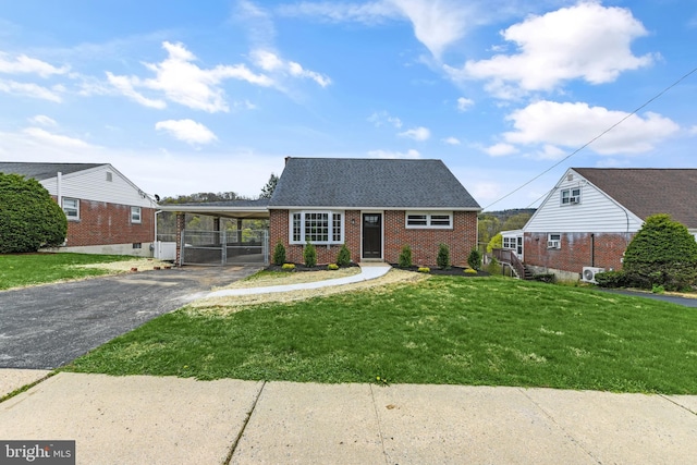 view of front of home with driveway, a front lawn, an attached carport, brick siding, and a shingled roof