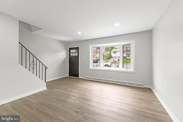 foyer featuring baseboards, stairway, wood finished floors, and baseboard heating