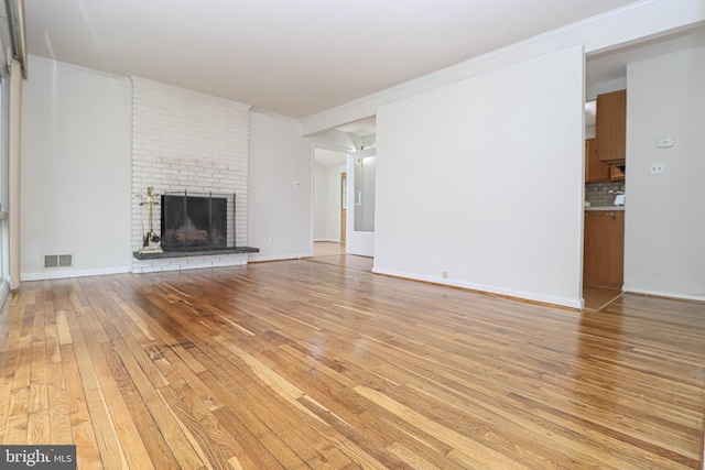 827 Crothers Ln, Rockville, MD 20852 - unfurnished living room with visible vents, baseboards, a brick fireplace, ornamental molding, and light wood finished floors