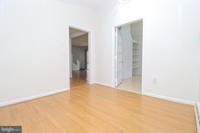 827 Crothers Ln, Rockville, MD 20852 - unfurnished bedroom with baseboard heating, a closet, baseboards, light wood-style flooring, and a walk in closet