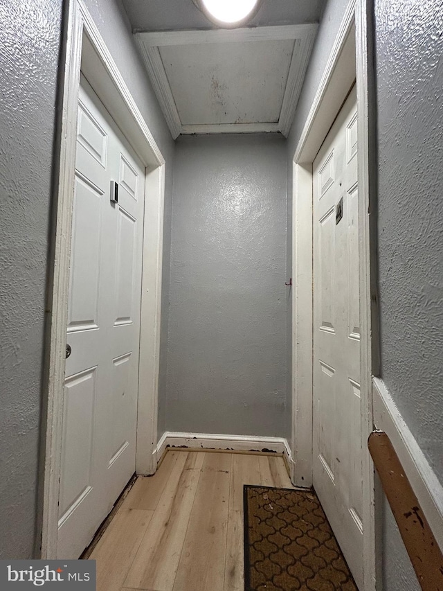 entryway featuring baseboards, light wood-style flooring, and a textured wall