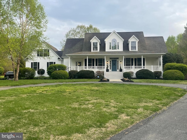 new england style home with a front yard and covered porch