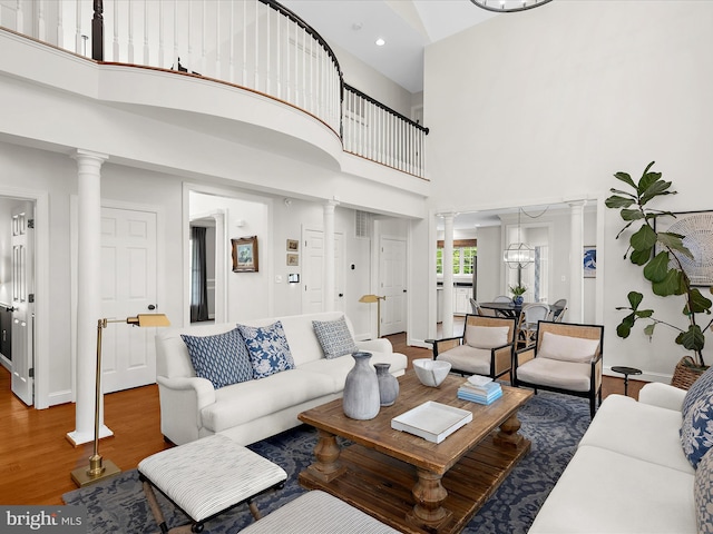 living area with baseboards, recessed lighting, decorative columns, wood finished floors, and a high ceiling
