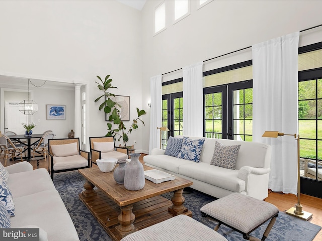 living area with wood finished floors, a notable chandelier, french doors, and a towering ceiling