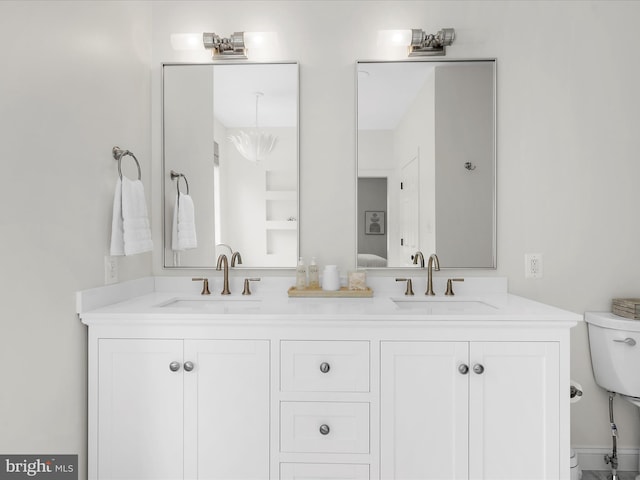 bathroom featuring toilet, double vanity, and a sink