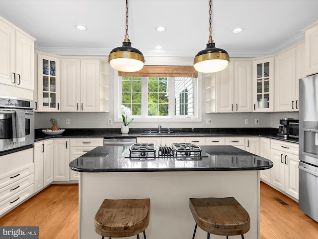 kitchen featuring a kitchen bar, a sink, stainless steel appliances, and light wood-style floors