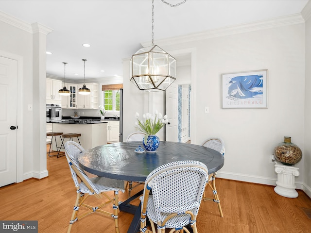 dining room featuring a chandelier, light wood-type flooring, ornamental molding, and baseboards