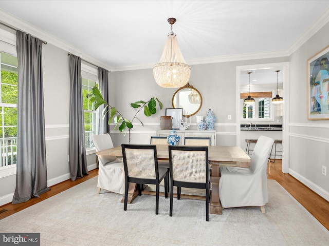 dining area featuring ornamental molding, an inviting chandelier, wood finished floors, and baseboards