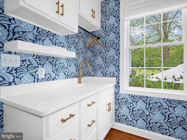 interior space featuring wood finished floors, wallpapered walls, and a sink