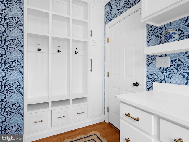 mudroom featuring wallpapered walls and wood finished floors