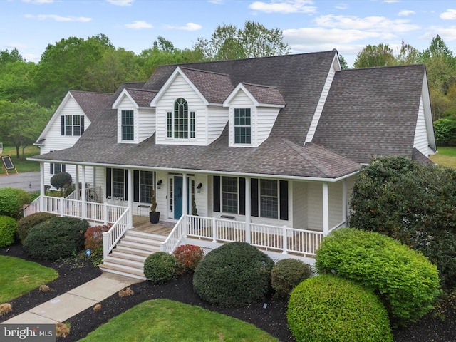 cape cod house featuring covered porch and a shingled roof