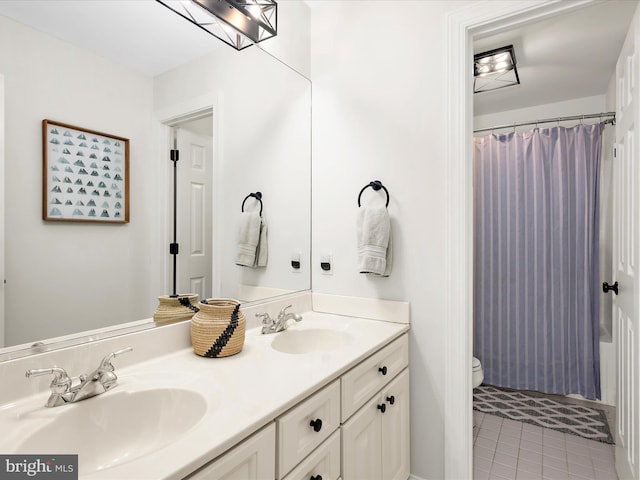 bathroom featuring double vanity, toilet, tile patterned floors, and a sink