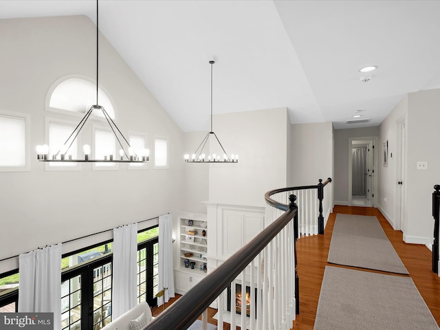 hallway featuring an upstairs landing, plenty of natural light, high vaulted ceiling, and a notable chandelier
