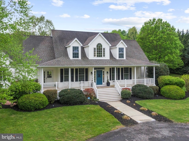view of front of property with roof with shingles, covered porch, and a front lawn