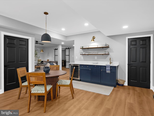 dining area with beverage cooler, a barn door, light wood-type flooring, and indoor wet bar
