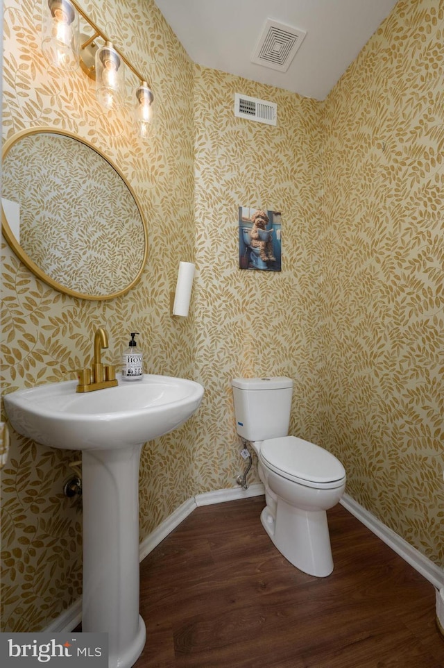 bathroom featuring wallpapered walls, wood finished floors, and visible vents