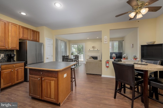 kitchen featuring a center island, brown cabinets, open floor plan, dark wood finished floors, and freestanding refrigerator