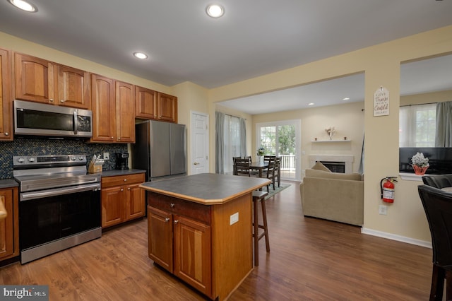 kitchen featuring a center island, dark wood-style floors, tasteful backsplash, open floor plan, and appliances with stainless steel finishes